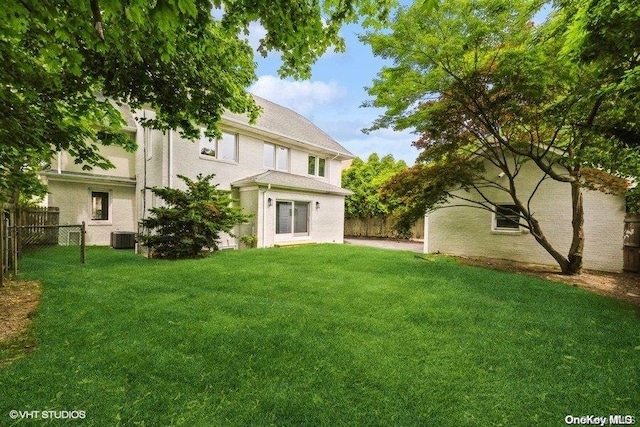 back of house featuring central AC unit and a lawn