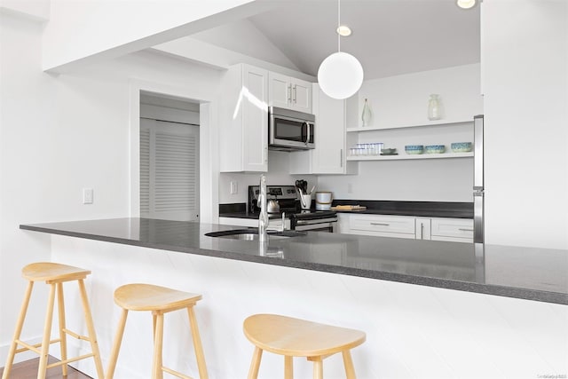 kitchen with white cabinets, a kitchen breakfast bar, kitchen peninsula, and appliances with stainless steel finishes