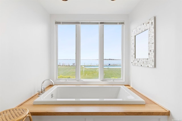 bathroom with a water view, a wealth of natural light, and a tub