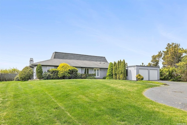 ranch-style home with a garage, an outbuilding, and a front yard