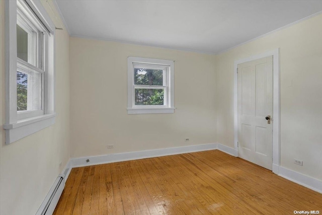 spare room with a baseboard heating unit, light wood-type flooring, and crown molding