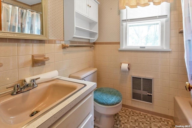 bathroom with vanity, heating unit, toilet, and tile walls