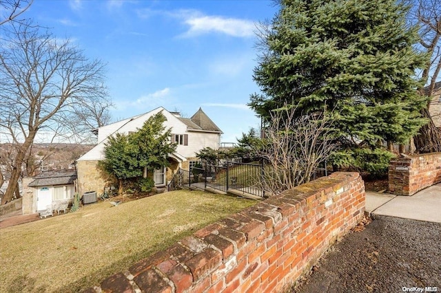 view of property hidden behind natural elements featuring central AC unit, a shed, and a front lawn