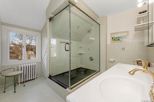 bathroom with tile patterned floors, radiator heating unit, sink, and tile walls