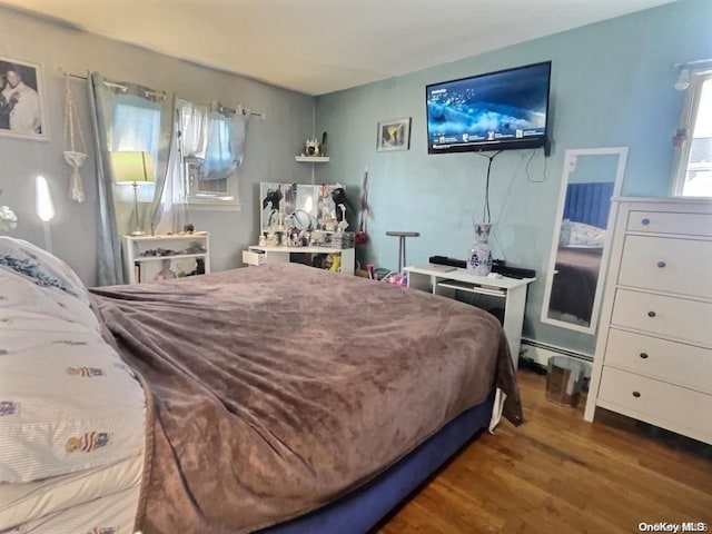 bedroom with hardwood / wood-style floors and a baseboard radiator