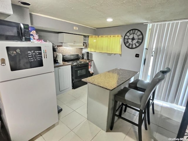 kitchen featuring backsplash, white cabinetry, a breakfast bar area, and black appliances