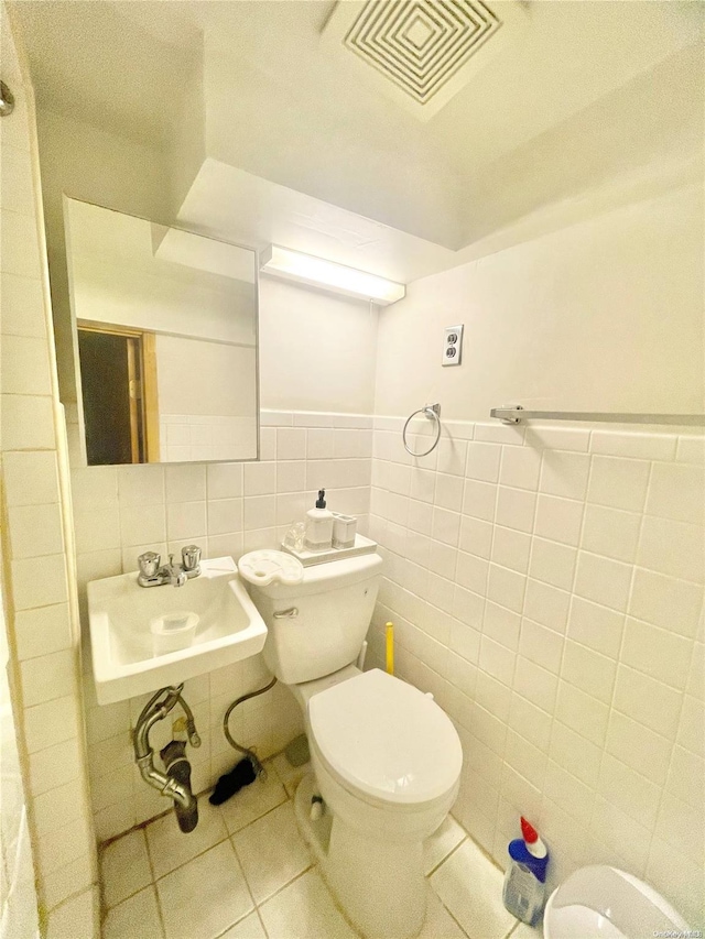 bathroom with tile patterned floors, toilet, sink, and tile walls