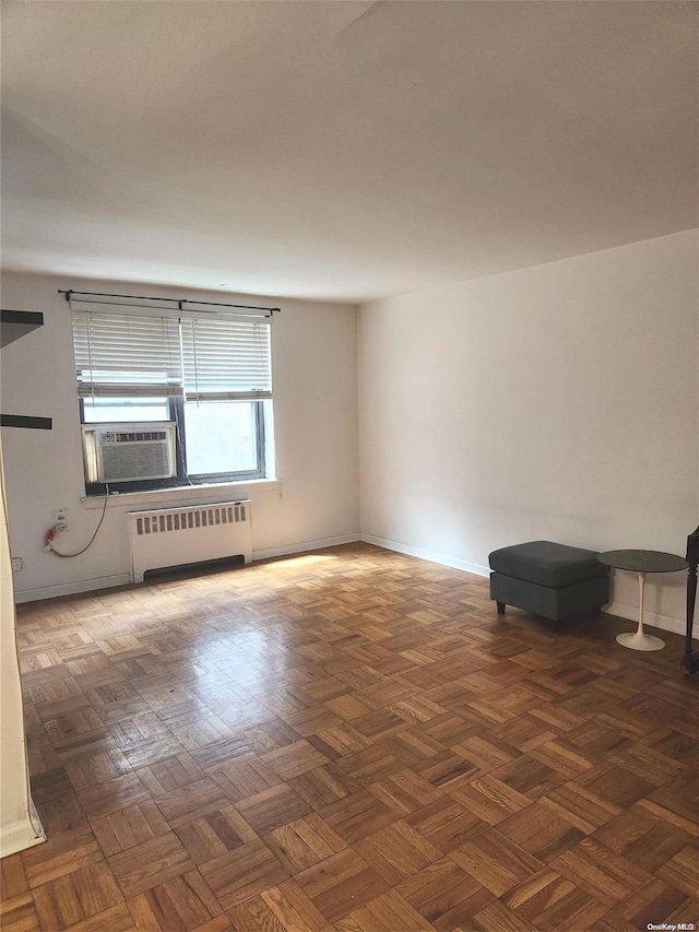 empty room with dark parquet floors, radiator, and cooling unit