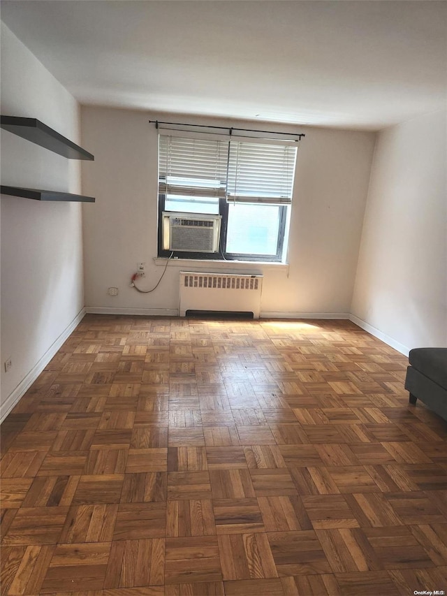 spare room with radiator heating unit, dark parquet floors, and cooling unit