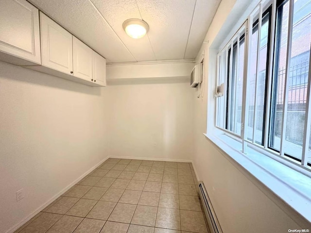 spacious closet with an AC wall unit, light tile patterned floors, and a baseboard heating unit