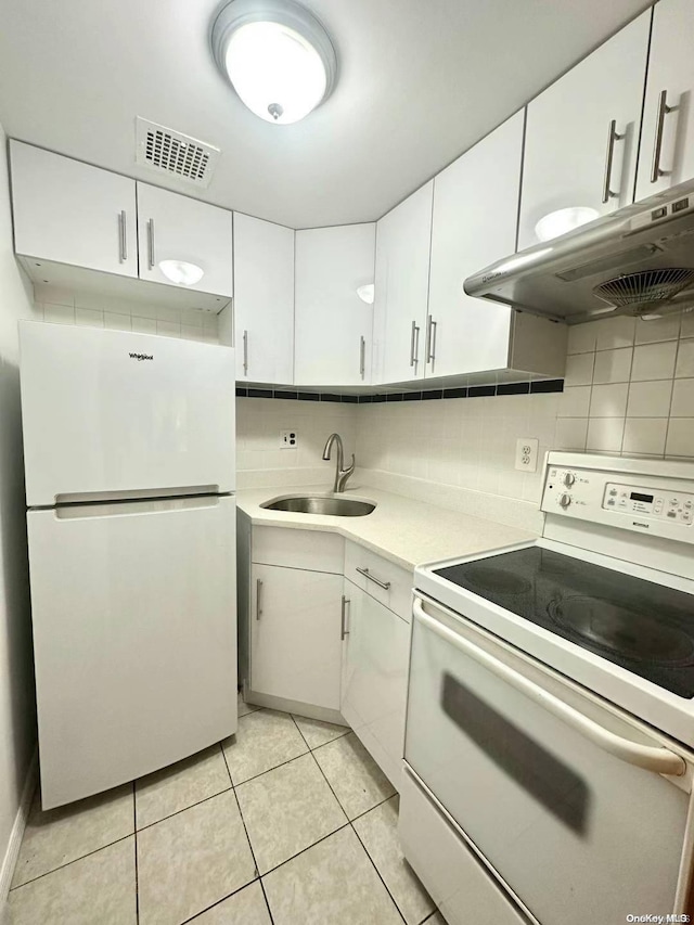 kitchen with white appliances, backsplash, white cabinets, sink, and light tile patterned floors