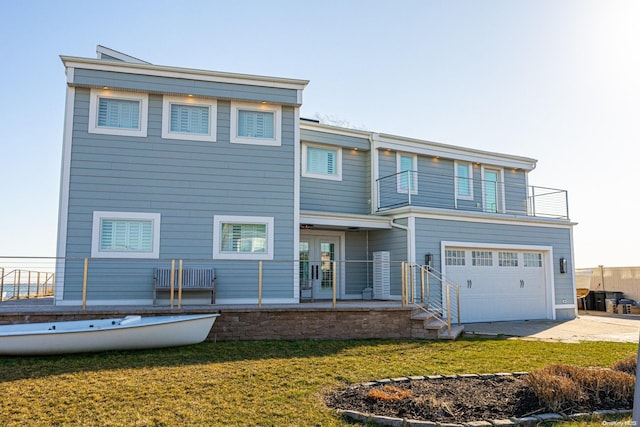 rear view of property with a lawn, a garage, and a balcony