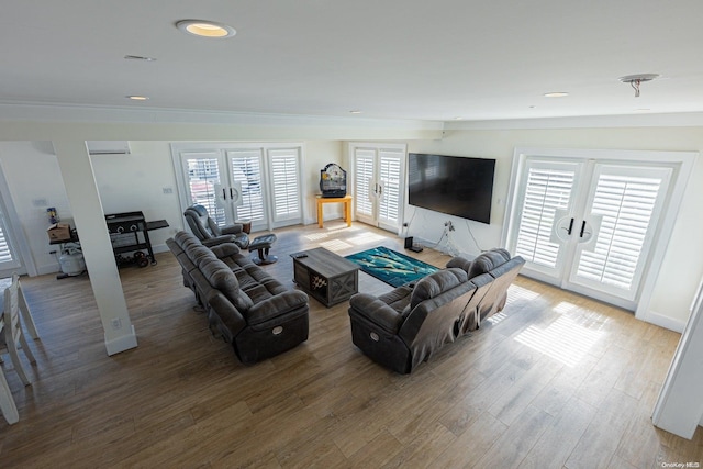 living room featuring french doors, a wall unit AC, a wealth of natural light, and hardwood / wood-style floors