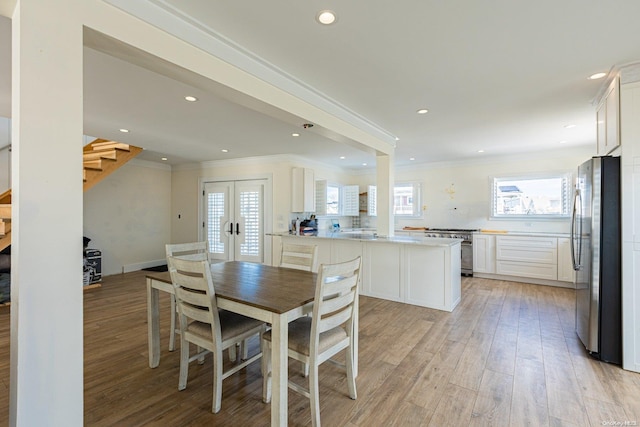 dining area featuring crown molding, light hardwood / wood-style flooring, and french doors