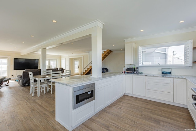 kitchen featuring kitchen peninsula, white cabinetry, stainless steel microwave, and a healthy amount of sunlight