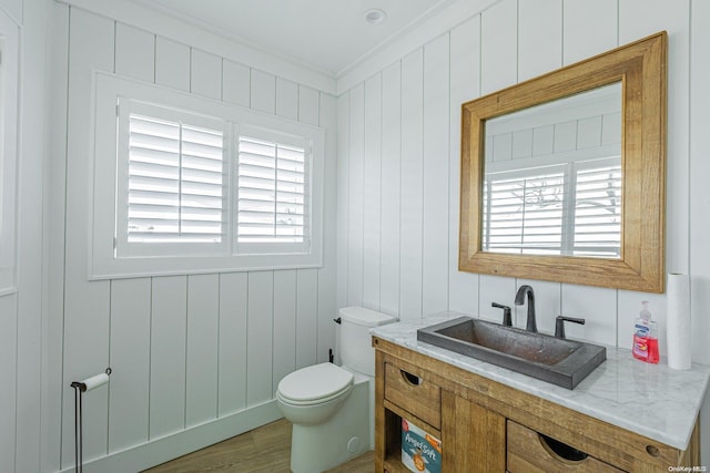 bathroom featuring wood-type flooring, toilet, a wealth of natural light, and ornamental molding