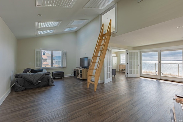 living room featuring french doors, a towering ceiling, a wealth of natural light, and dark wood-type flooring