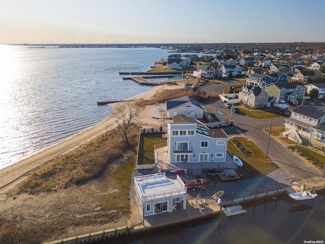 aerial view at dusk featuring a view of the beach and a water view