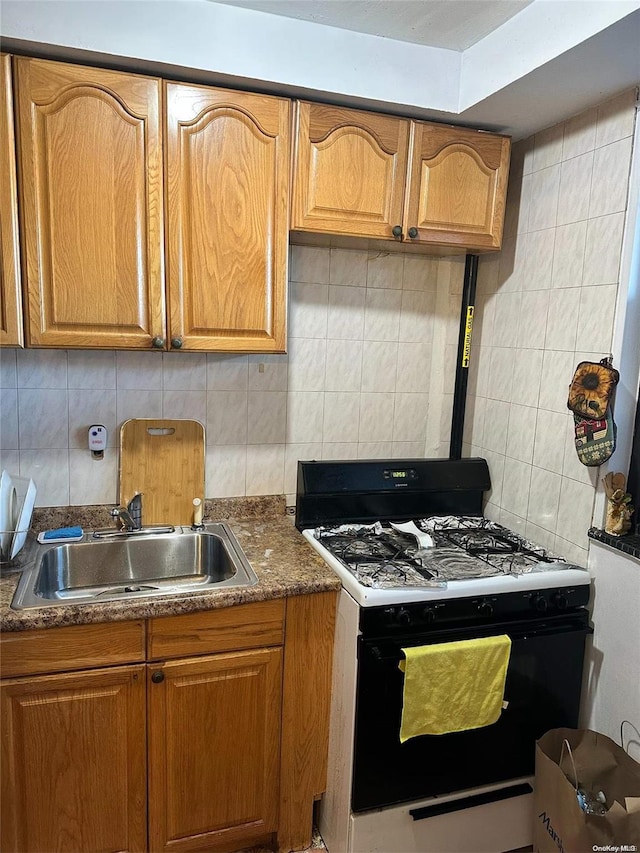 kitchen featuring decorative backsplash, white gas range, and sink