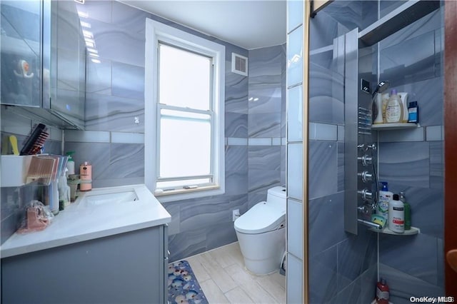 bathroom featuring vanity, toilet, and tile walls