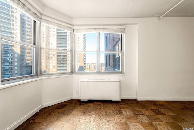 unfurnished room featuring dark parquet floors and radiator