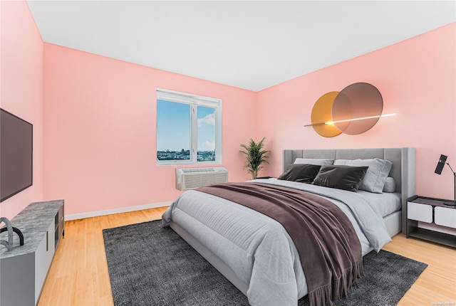 bedroom featuring hardwood / wood-style floors and an AC wall unit