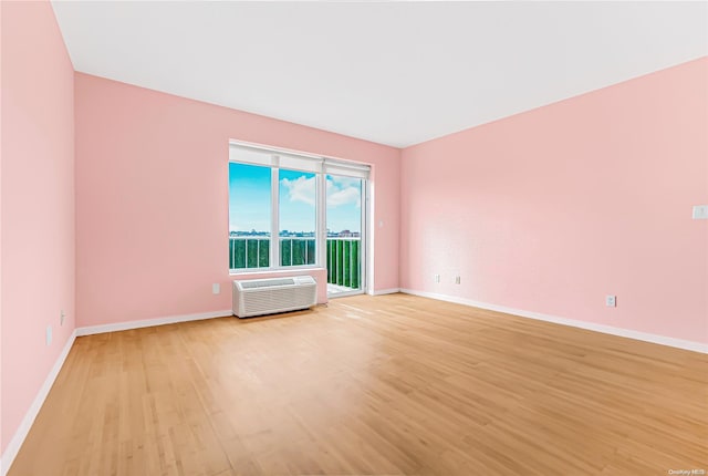 spare room with a wall mounted air conditioner and light hardwood / wood-style flooring