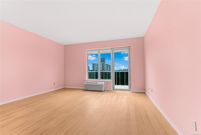 spare room featuring a wall mounted AC and light hardwood / wood-style floors