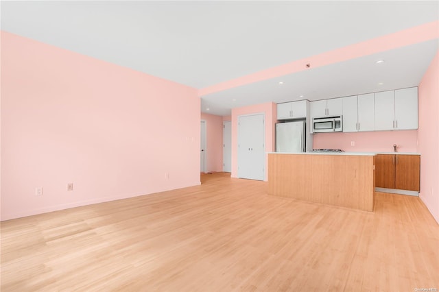 kitchen featuring light hardwood / wood-style floors, a kitchen island, white cabinetry, and stainless steel appliances