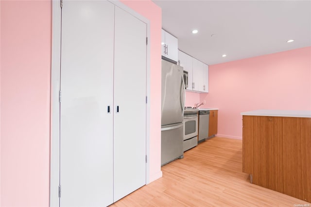 kitchen with white cabinetry, stainless steel appliances, and light wood-type flooring