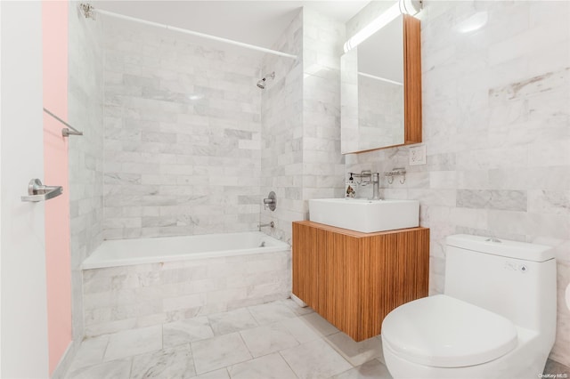 full bathroom with tile walls, vanity, tiled shower / bath combo, and toilet