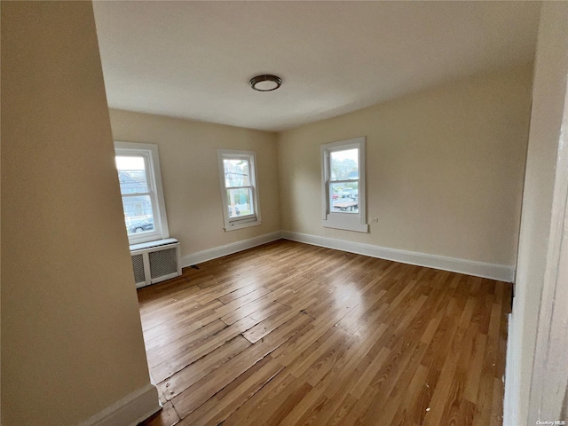 spare room featuring radiator and light hardwood / wood-style flooring