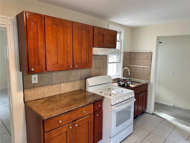 kitchen with sink, light tile patterned flooring, white range, and backsplash