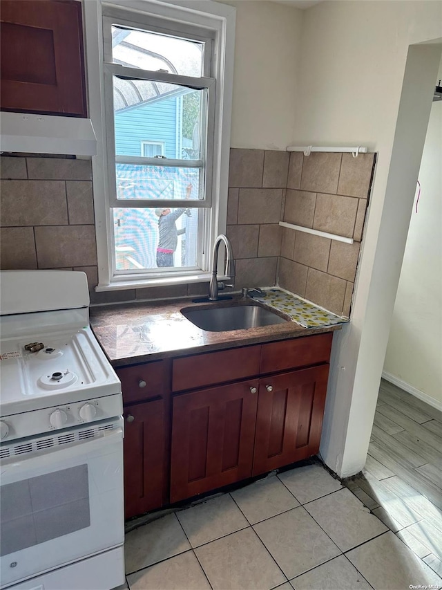 kitchen with sink, light tile patterned floors, and white stove