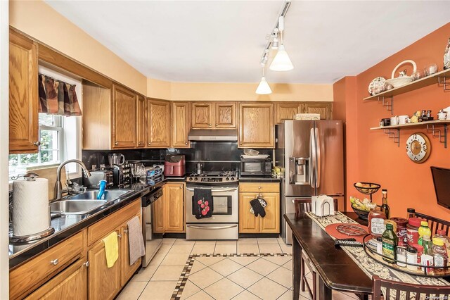 kitchen with sink, hanging light fixtures, backsplash, light tile patterned flooring, and appliances with stainless steel finishes