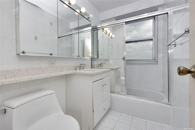 full bathroom featuring vanity, tile patterned floors, bath / shower combo with glass door, toilet, and tile walls