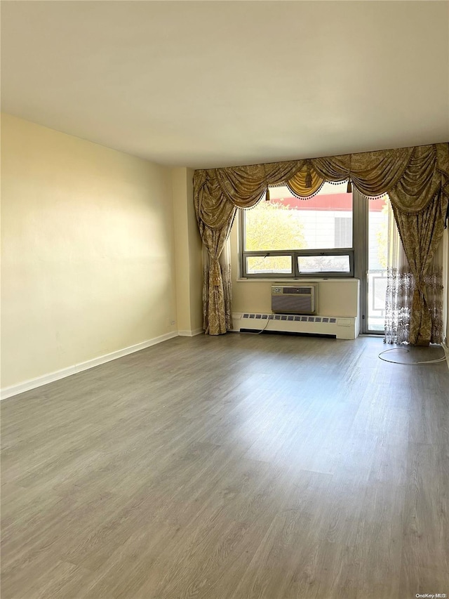 unfurnished living room featuring a wealth of natural light, a baseboard radiator, and hardwood / wood-style flooring