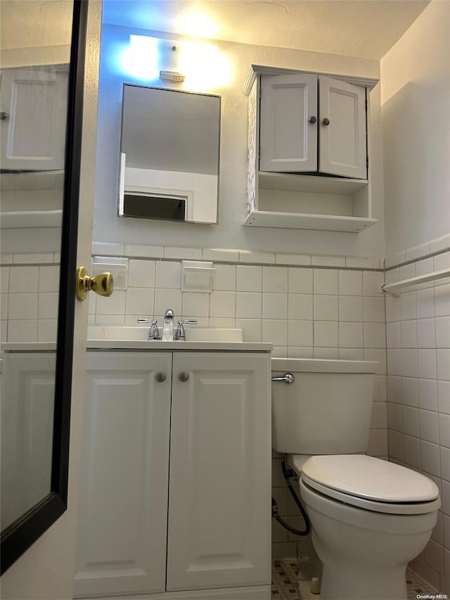 bathroom with vanity, toilet, and tile walls