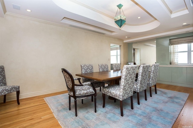 dining room featuring a tray ceiling, ornamental molding, and hardwood / wood-style flooring