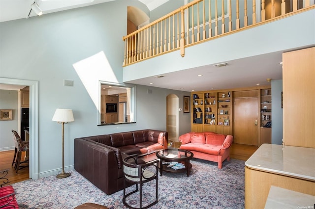 living room with a towering ceiling and hardwood / wood-style flooring