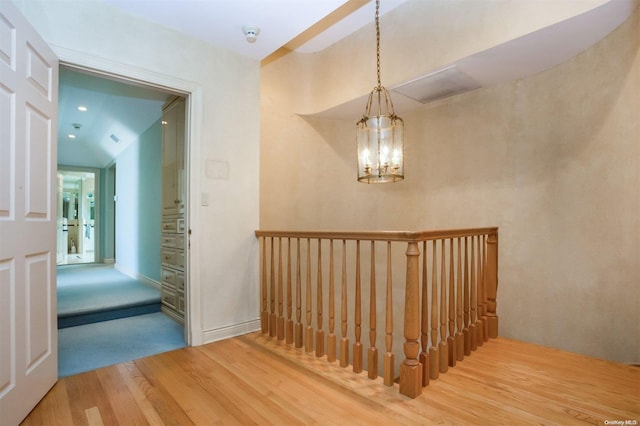 stairway with hardwood / wood-style floors and a notable chandelier