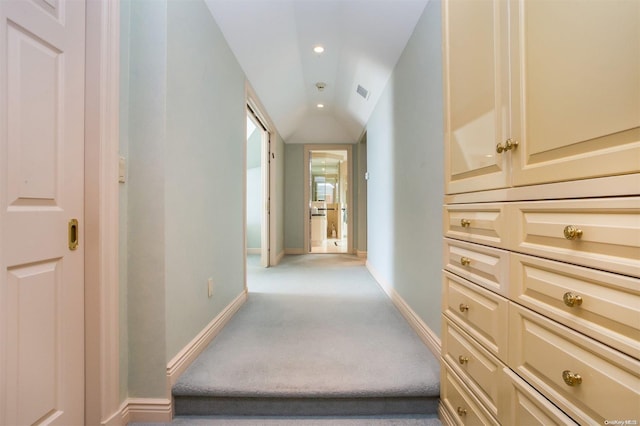 hallway with light colored carpet and vaulted ceiling