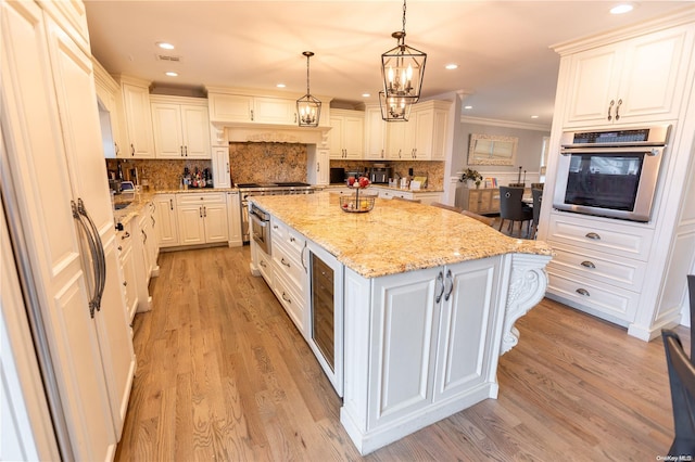 kitchen with white cabinets, appliances with stainless steel finishes, a center island, and light wood-type flooring