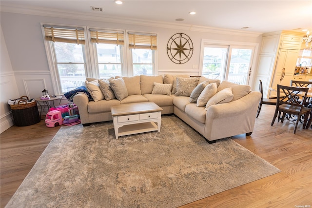 living room with crown molding, plenty of natural light, and hardwood / wood-style flooring