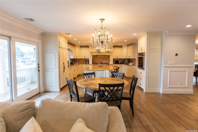 dining space with light hardwood / wood-style floors, a notable chandelier, and ornamental molding