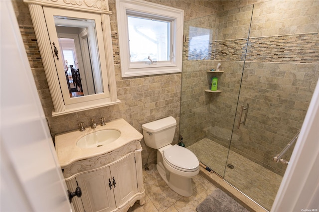 bathroom featuring tile patterned floors, an enclosed shower, toilet, vanity, and tile walls