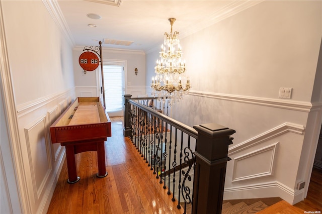 hallway with hardwood / wood-style floors, ornamental molding, and a chandelier