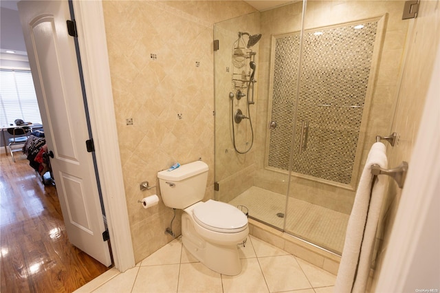 bathroom with a shower with door, wood-type flooring, tile walls, and toilet