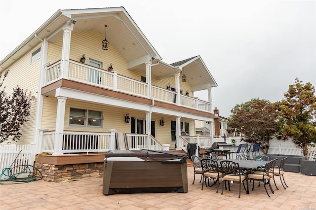 back of property featuring a balcony, a hot tub, and a patio area