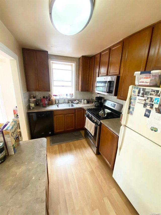 kitchen with stainless steel appliances, tasteful backsplash, light hardwood / wood-style floors, and sink